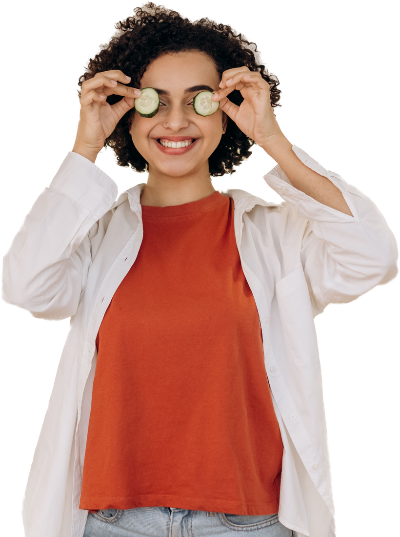 Person holding cucumber slices playfully over their eyes